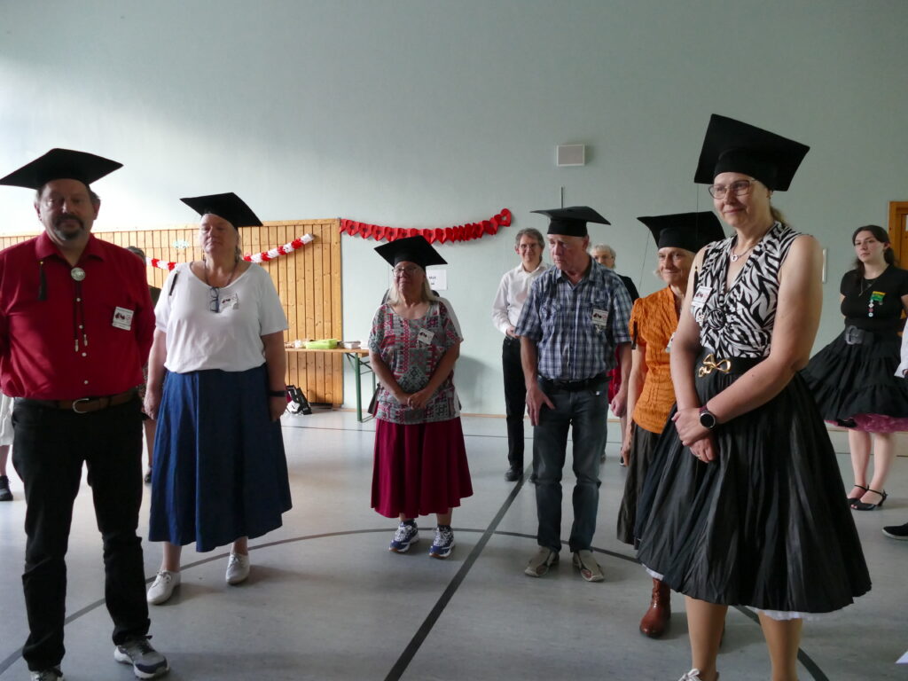 Gruppenbild von 6  glücklichen Tänzern und Tänzerinnen mit Doktorhut
